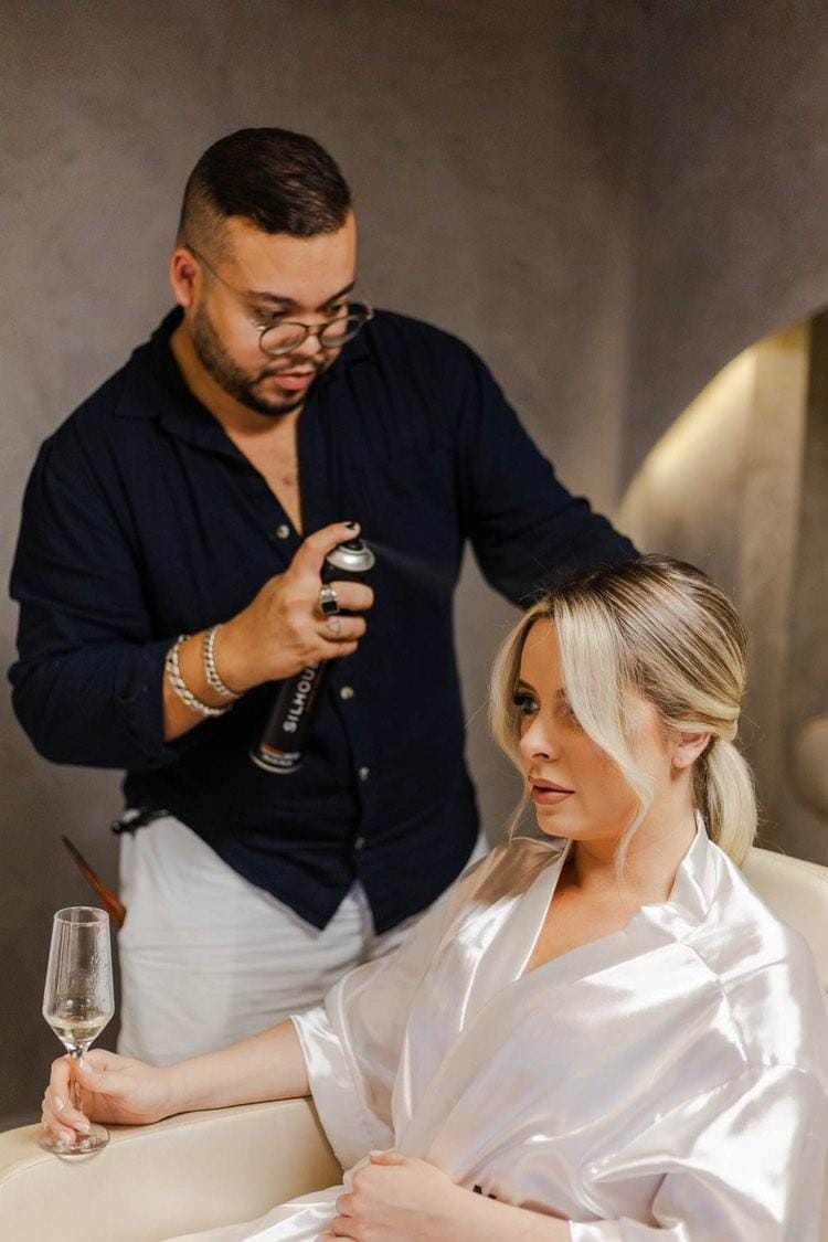 Niko Oliveira, especialista em cor, corte e penteados, finalizando o penteado de uma cliente no Aura Concept