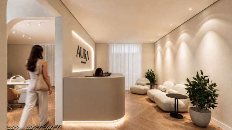 Render 3D da recepção do Aura Concept: balcão de atendimento com o logo iluminado, poltronas e plantas em tons neutros