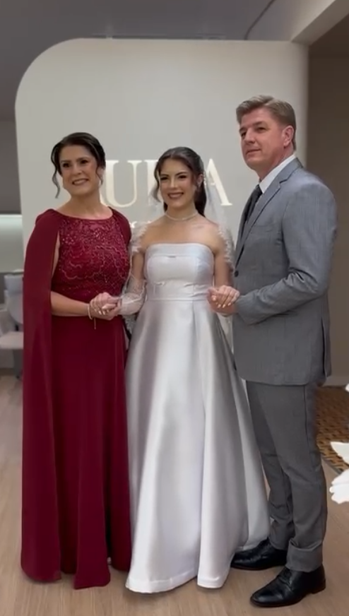 Noiva ao lado da mãe e do pai, em frente ao letreiro do Aura Concept